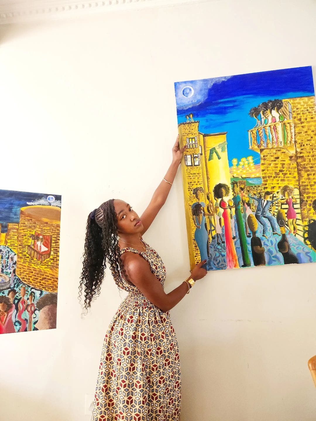 Sisanda Ngcakani of Naomi Artworks placing an original painting on the wall during a staging